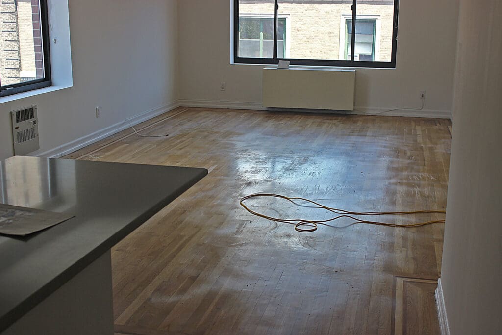 Before hardwood floor cleaning in Manhattan apartment showing dull finish, dirt buildup, and surface residue.